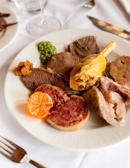 Piatto della Trattoria La Busa con bolliti, arrosti, salse e contorni, inquadratura verticale.