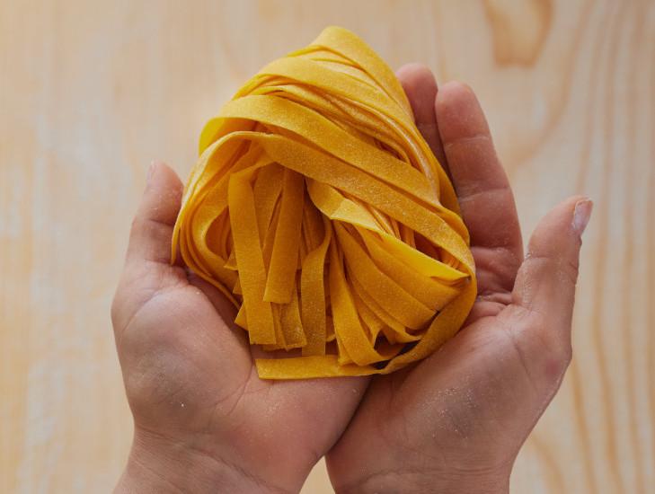 Una cuoca tiene tra le mani un nido di tagliatelle fresche fatte a mano alla Trattoria La Busa.